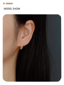 Close-up of golden chain style earring hoop worn on a model with minimalist metal design