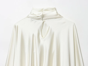 Detail of a white satin mini dress featuring back neck button closure and cutout design