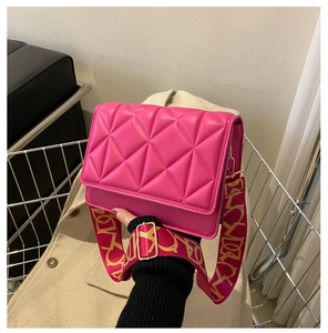 Detail of fuchsia quilted crossbody bag with stylish wide patterned strap and metal buckle