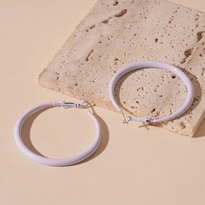 Detail view of large matte lavender geometric hoop earrings on natural stone background