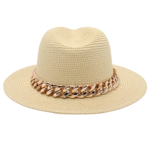 Gros plan sur la texture tissée fine et le détail de la chaîne dorée du chapeau Panama