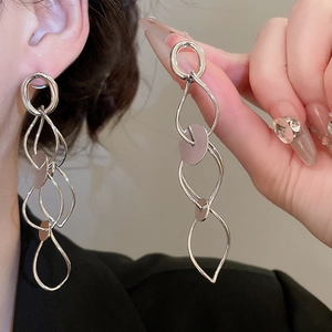 Detail of silver long multilayer geometric hollow earrings worn on ear showing drape