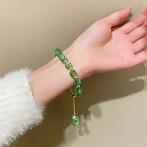 Green crystal beaded bracelet with adjustable gold slide clasp worn on a plush sleeve