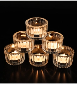Close-up of ribbed crystal glass tea light holders with warm glowing candles
