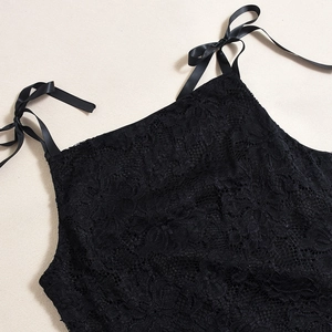 Detailed close-up of intricate black lace texture and satin bow ribbon on the dress