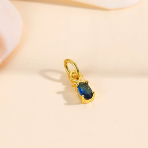 Macro shot of 18k gold plated pineapple pendant featuring a blue oval zircon stone