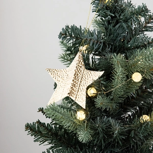 Étoile de Noël dorée avec texture martelée suspendue sur des branches de sapin vert