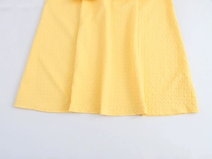 Detail of yellow dress fabric with embossed puff texture and soft cascading ruffles