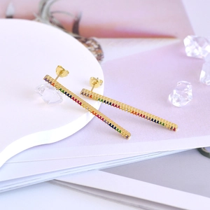 Macro detail of gold bar stud earrings featuring colorful pave-set cubic zirconia stones