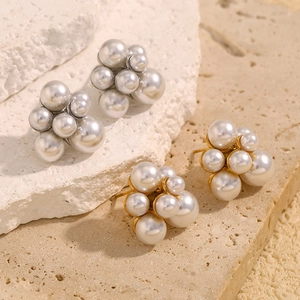 Detailed view of cluster pearl stud earrings in gold and silver finishes on stone