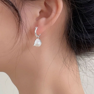 Close-up of elegant 925 silver hoop earrings with irregular baroque pearls on model