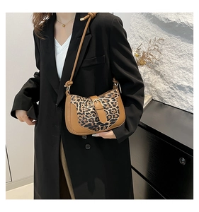 Detailed side view of leopard print shoulder bag with brown leather strap and gold buckle