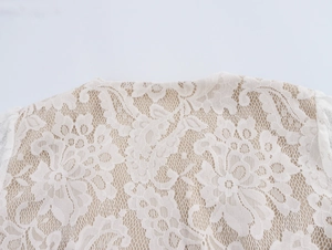 Detailed macro view of white floral lace texture and intricate mesh on the top's neckline