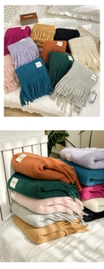 Close-up of thick knit scarves with fringe details in various colors and handmade label