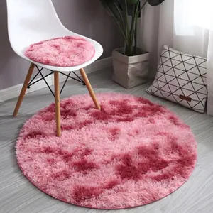 Detail of round plush rug in pink gradient with long fibers on modern grey wood floor