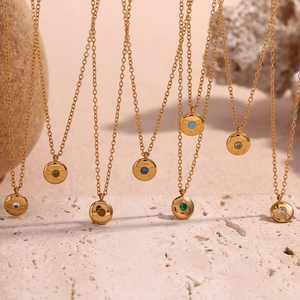 Close-up of 18K gold-plated necklaces with colorful birthstone charms on natural stone