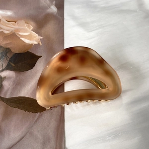 Detail of elegant cream leopard acetate hair claw clip with golden metal teeth
