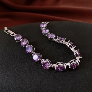 Detail of silver tennis bracelet with oval purple zircon gemstones on velvet