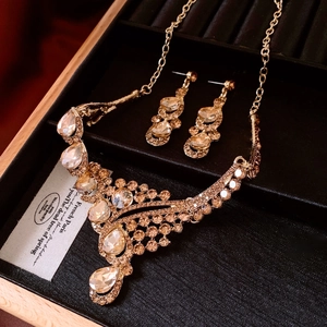 Detail view of vintage champagne rhinestone necklace and earring set on black velvet