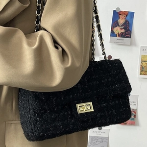 Fashionable black tweed flap bag with gold chain and rectangular lock on model