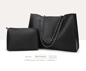 Macro shot of black quilted faux leather tote bag and matching zippered clutch set