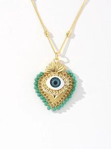 Detailed view of heart-shaped evil eye pendant with green beads and golden chain