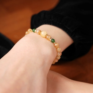 Détail d'un bracelet en perles avec cristaux dorés et perles de jade vert au poignet
