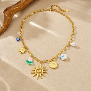 Gold stainless steel necklace with sun, floral, and pearl pendants on beige surface