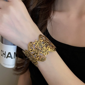 Detail shot of vintage golden hollow flower cuff bracelet with paisley metal patterns