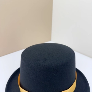 Detail of wool top hat featuring a golden ribbon band and textured black felt finish