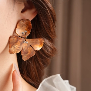 Detailed view of resin flower earrings with marble texture and rhinestones on a model