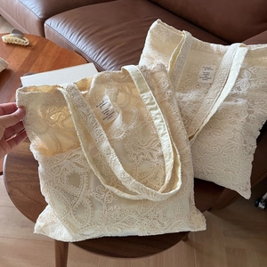 Detailed macro view of beige lace embroidery pattern and texture on a tote bag