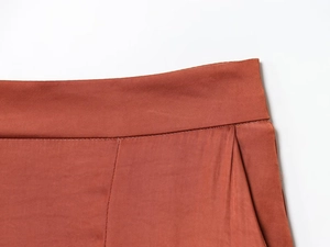 Detailopname van de taille-stiksels en effen geweven stof van een roestbruine broek