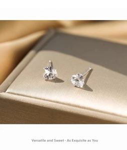 Detailed macro view of 999 silver heart-shaped zircon studs on a premium jewelry box