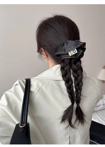 Detail of blue denim scrunchie with yellow stitching on a braided hairstyle