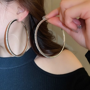 Close-up of large silver hoop earrings with shimmering crystals on model