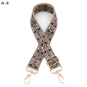 Close-up of ethnic floral bag strap with golden metal buckles and adjustable slider
