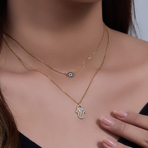 Close-up of gold-plated S925 silver double necklace with Hamsa hand and Evil Eye charms