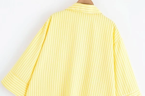 Detail view of yellow striped V-neck shirt showing the back shoulder and fabric texture