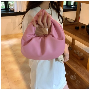 Detail of pink knotted handle on a pleated crescent moon handbag in soft faux leather