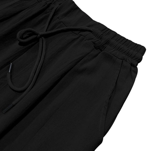 Detail of men's black linen trousers featuring elastic drawstring waist and side pockets