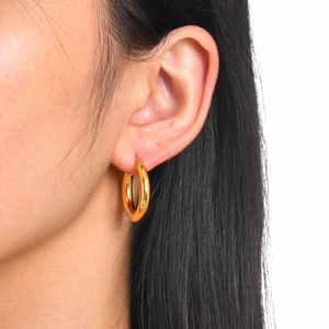 Close-up of polished 18k gold plated stainless steel hoop earrings worn on ear
