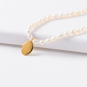 Close-up of a French vintage gold oval pendant on a lustrous natural pearl necklace