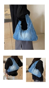 Détail du sac hobo en jean bleu avec plis en éventail et texture vintage délavée