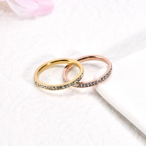 Close-up of gold and rose gold stainless steel rings with zircon stones on white paper