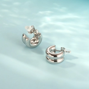 Macro view of double layered silver hoop earrings with polished finish on water background