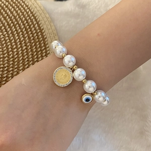 Detailed close-up of beaded evil eye bracelet with gold coin charm on a woman wrist