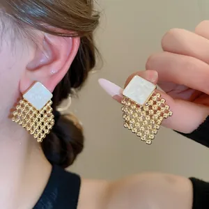Elegant woven diamond-shaped gold drop earrings with white square marble textured inlay