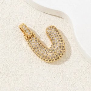Macro shot of gold-plated letter U pendant with shimmering pavé cubic zirconia