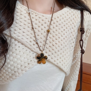 Macro detail of amber resin flower pendant with gold edging on woven cord necklace